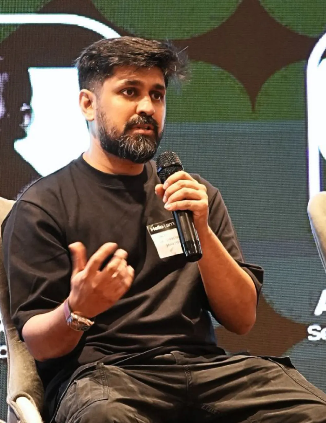 Aakreit Sachdeva speaking on a panel, holding a microphone